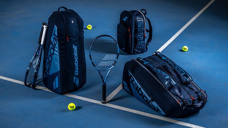 Babolat Pure Drive 2025 tennis racquets and bags arranged on a blue court