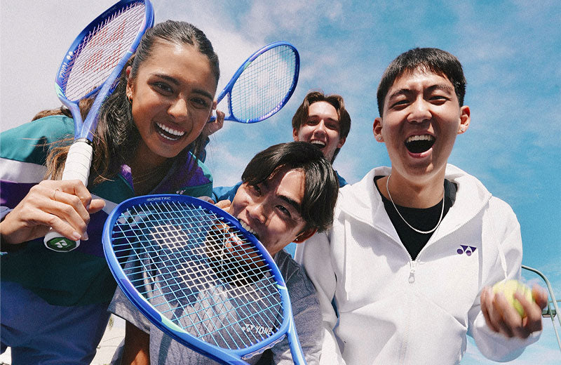 Lifestyle image of a group of tennis players posing with Yonex EZONE racquets