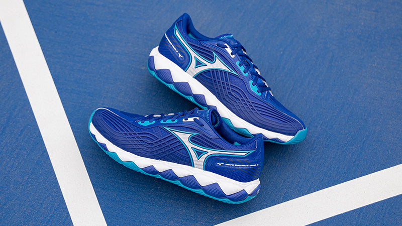 Mizuno Wave Enforce Tour 2 tennis shoes on a blue court