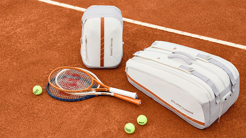 Wilson Roland Garros 2025 tennis racquets and bags displayed on a clay court